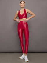 Model wears a bright red shiny, liquidlike sports bra with a v neck. 