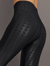 Model wears a pair of high waisted black houndstooth print leggings. 