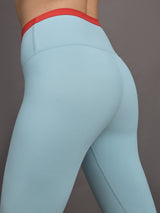 Model wears a light blue performance legging with a red waistline. 