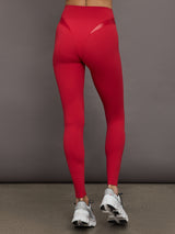 Model wears a sleek, high waisted bright red legging with shiny contoured hip detailing lines. 