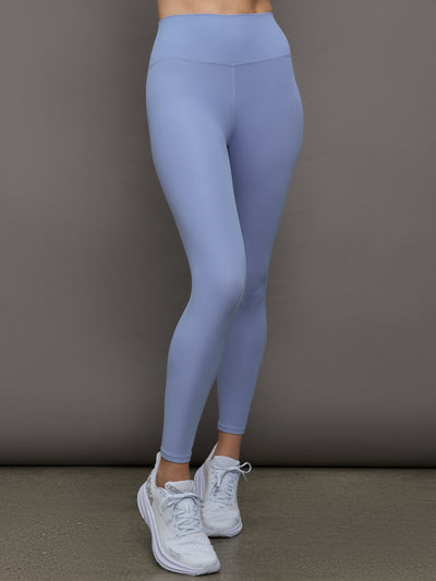 Model wears a pair of high waisted periwinkle colored ribbed leggings. 