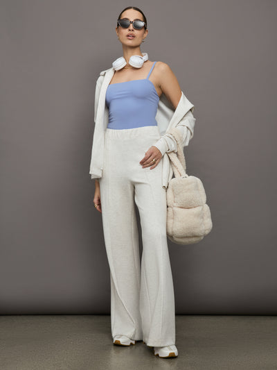 Model wears a periwinkle colored body suit with a straight neckline across the chest and thin straps. 