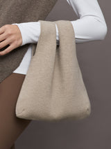 Model wears a double handled taupe linen textured bag on her arm.