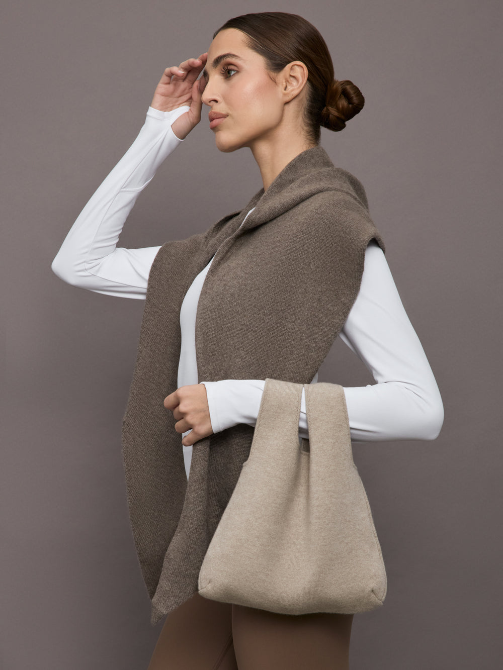 Model wears a double handled taupe linen textured bag on her arm.