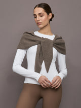 Model wears a muted brown colored hooded scarf over her shoulders. 