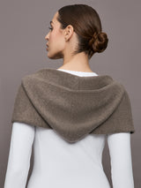 Model wears a muted brown colored hooded scarf over her shoulders. 