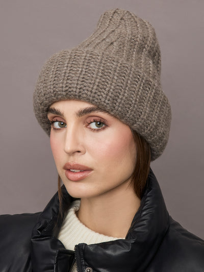 Model wears a light brown thick knit beanie. 