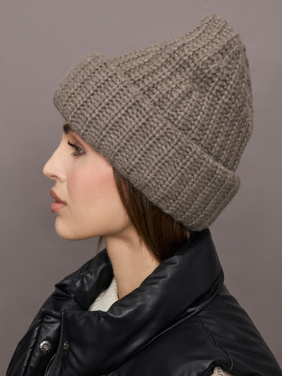 Model wears a light brown thick knit beanie. 