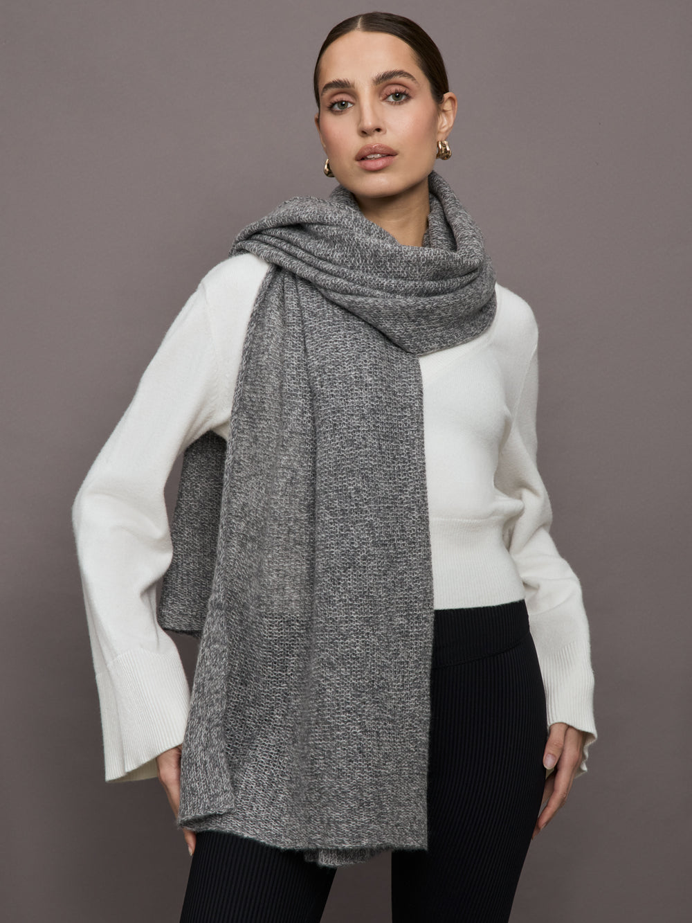 Model wears an oversized heathered grey colored scarf around her neck. 