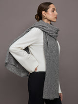 Model wears an oversized heathered grey colored scarf around her neck. 