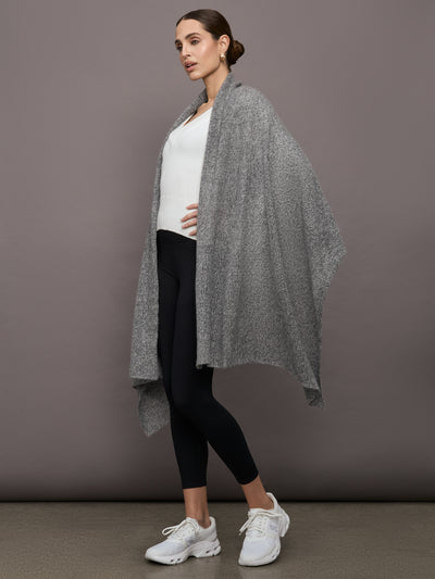 Model wears an oversized heathered grey colored scarf as a shawl.