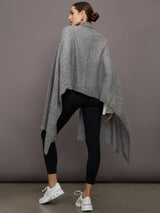 Model wears an oversized heathered grey colored scarf as a shawl.