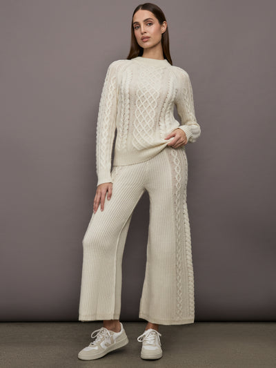 Model wearing a cream colored vertically textured wide cable knit sweater. 