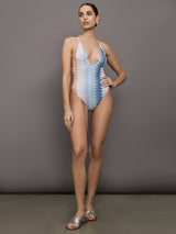 Model wears a one piece high cut bathing suit with a deep v neck and multicolored zig zag pattern. 