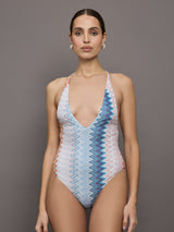 Model wears a one piece high cut bathing suit with a deep v neck and multicolored zig zag pattern. 